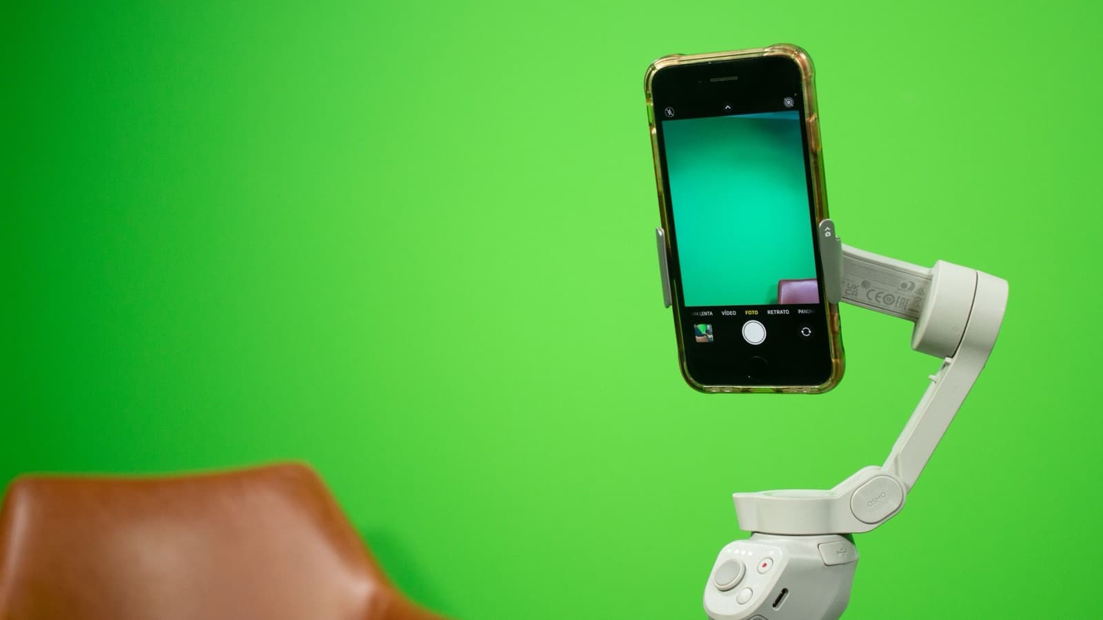 Un smartphone tenu à la verticale sur un stabilisateur, qui filme devant un fond vert